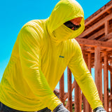 Man wearing a hi-vis yellow GOBI Helio UPF Sun Hoodie with hood and built-in face cover pulled up at a construction site, with wood framing in the background.