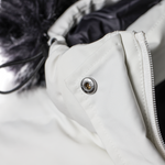 Close-up of a white jacket with a button and zipper detail.