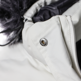 Close-up of a white jacket with a button and zipper detail.