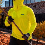 Man in a hi-vis yellow GOBI Helio UPF Sun Hoodie with hood and face cover up, holding a long-handled tool while wearing work gloves and a cap on an outdoor job site.