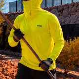 Man in a hi-vis yellow GOBI Helio UPF Sun Hoodie with hood and face cover up, holding a long-handled tool while wearing work gloves and a cap on an outdoor job site.