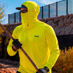 Man in a hi-vis yellow GOBI Helio UPF Sun Hoodie with hood and face cover up, holding a long-handled tool while wearing work gloves and a cap on an outdoor job site.
