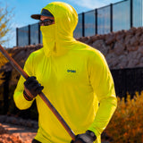 Man in a hi-vis yellow GOBI Helio UPF Sun Hoodie with hood and face cover up, holding a long-handled tool while wearing work gloves and a cap on an outdoor job site.