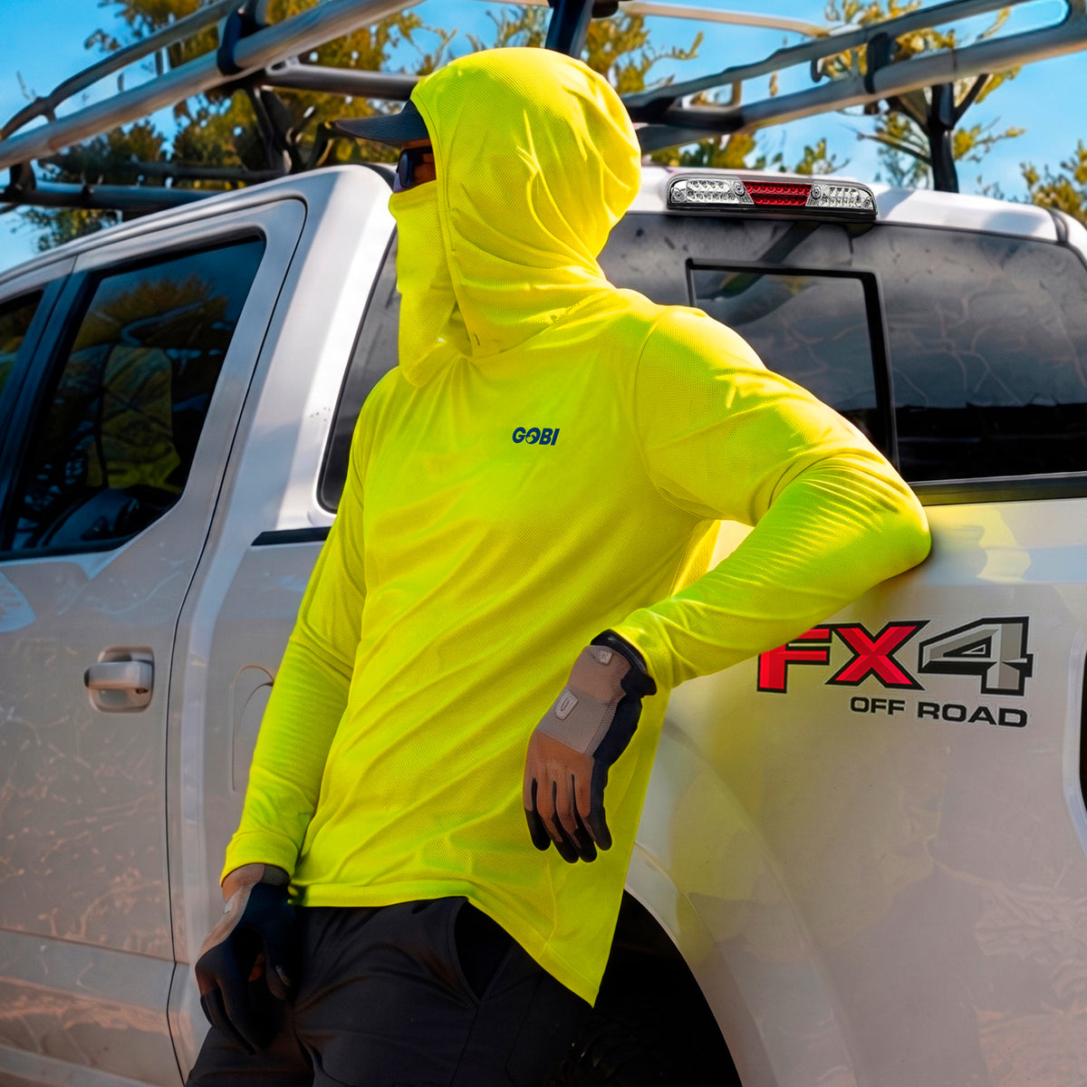 Man Leaning on truck wearing yellow Helio hoodie